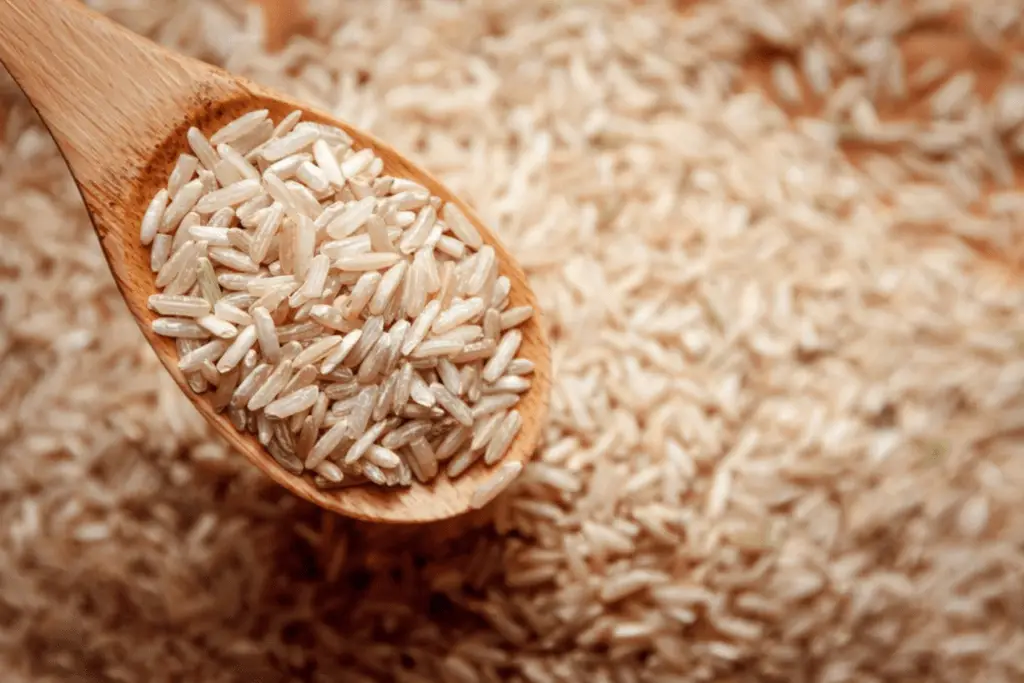 "Wooden spoon filled with uncooked Brown Basmati Rice, showcasing its texture and grains