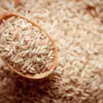 "Wooden spoon filled with uncooked Brown Basmati Rice, showcasing its texture and grains