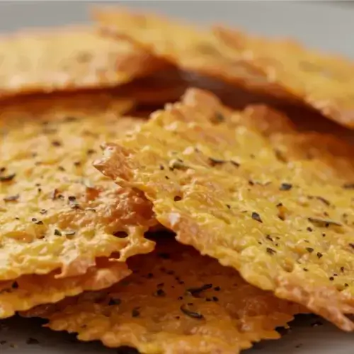 Crispy cottage cheese chips with black pepper and herbs, served on a plate.