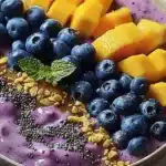 Delicious mango blueberry smoothie bowl topped with fresh fruits and seeds