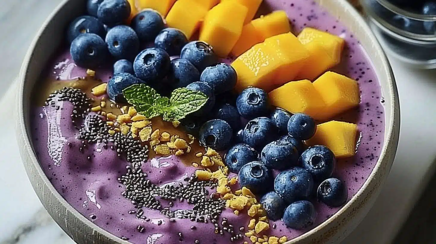 Delicious mango blueberry smoothie bowl topped with fresh fruits and seeds