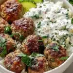 Baked Greek meatballs served in a rice bowl with fresh ingredients.