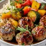 Delicious herb meatballs with roasted vegetables and a side of rice on a plate
